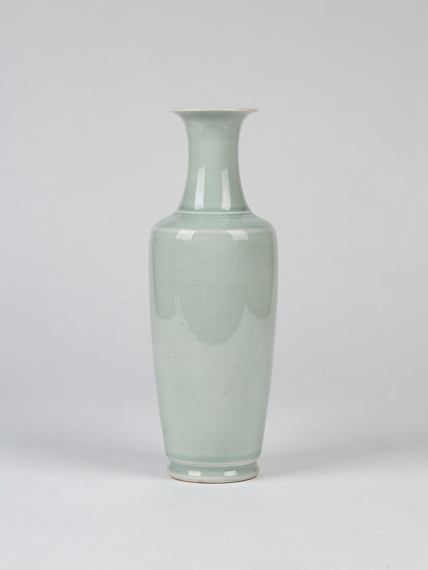 A tall slender porcelain vase with a pale green celadon glaze and a faint ring at the shoulder.