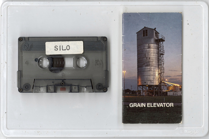 A smoky gray cassette with a typewritten label reading Silo beside its J-card with a photo of a grain elevator at dusk and the words Grain Elevator.