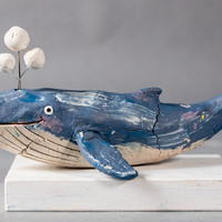 Long clay blue whale with a pale belly, scratched throat lines, a smiling eye and three white clay bubbles on a wire above its blowhole.